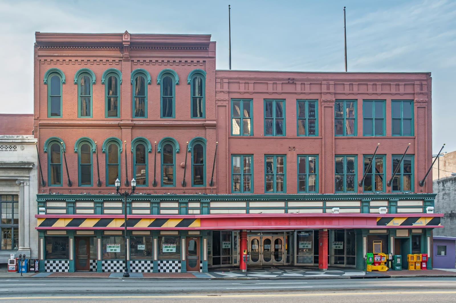 Two historic brick buildings stand side by side, arched windows on the upper floor.