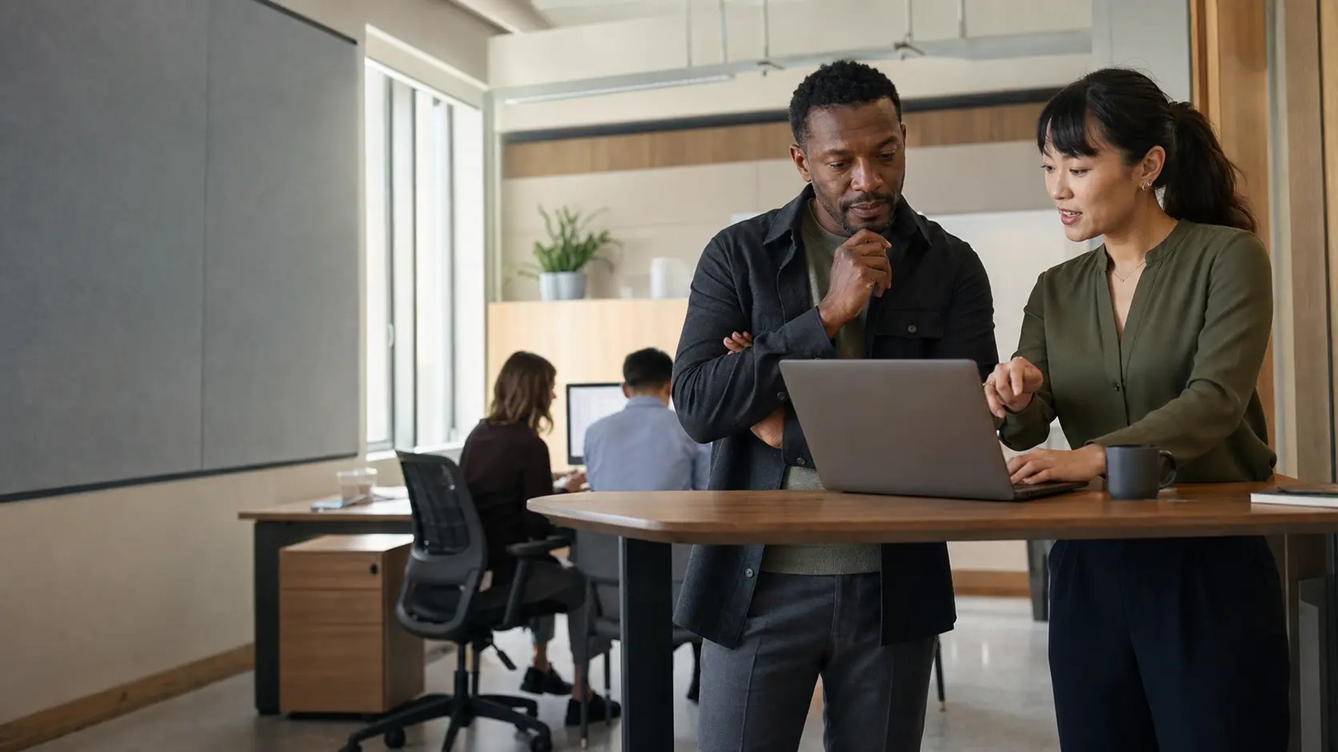 A clean modern workspace with a laptop and dual external monitors on a wood desk.